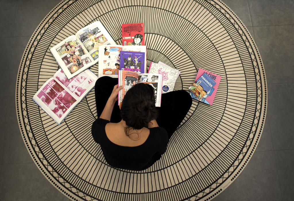 vue du dessus d'une femme qui lit des livres sur le sol, avec d'autres livres éparpillés en face d'elle